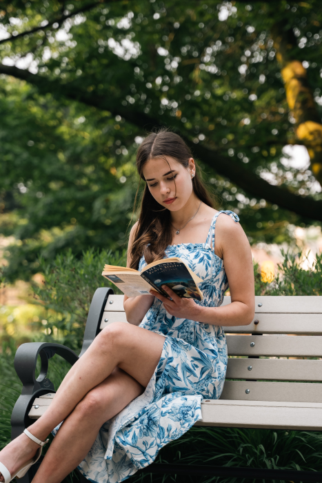 Beautiful girl in a dress reading a book on a bench. book blog list and book blogger list (flyintobooks.com)