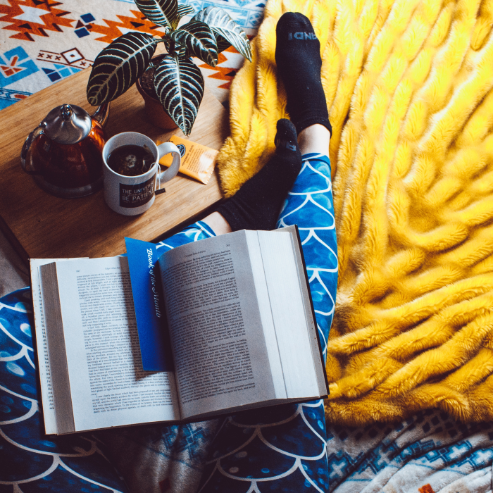 Woman in blue tights reading a book on a yellow rug.