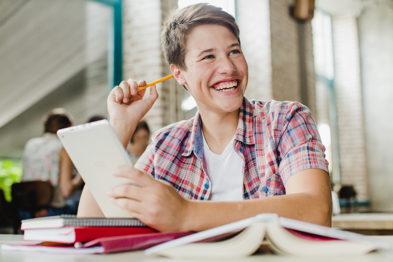 Boy with pencil and tablet smiling. how to promote a self-published book  (Flyintobooks.com)